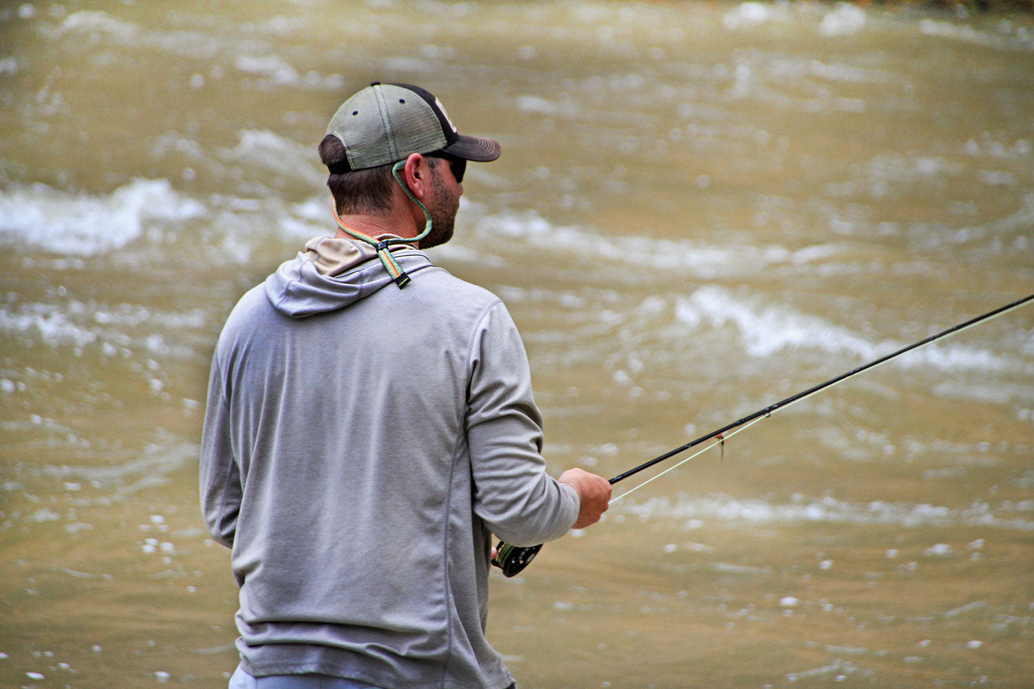 Man fishing in a river wearing Croakies eyewear retainers